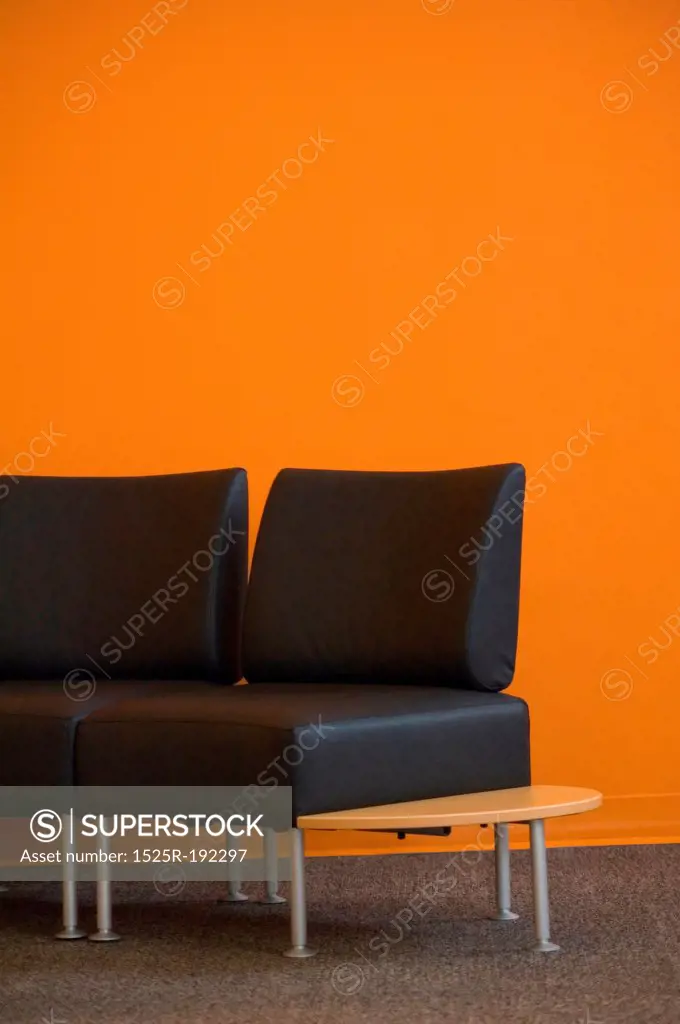 Empty chairs against a bright orange wall.