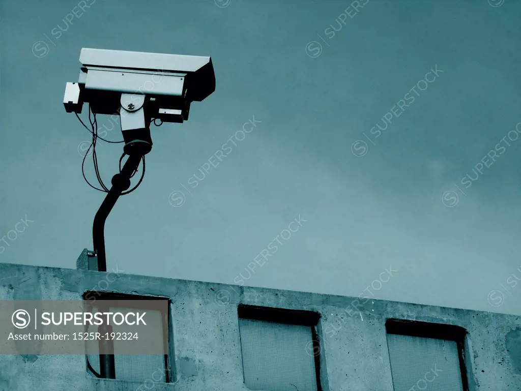 Security surveillance camera on rooftop of urban building.