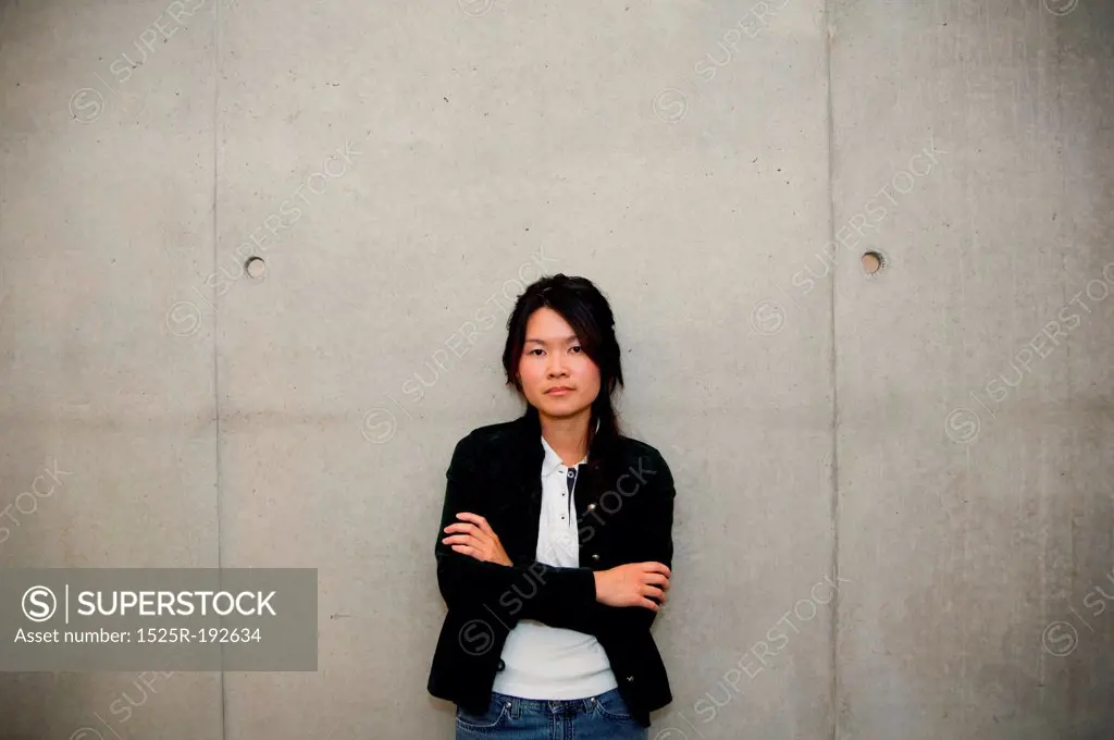 Serious Asian girl against cement wall.
