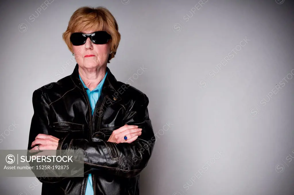 Older senior woman in a black leather jacket and sunglasses.