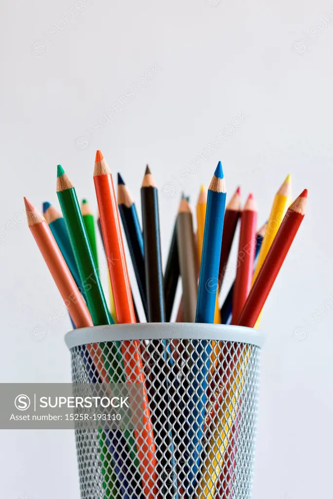 Sharpened colored pencils in pencil holder, on white background.