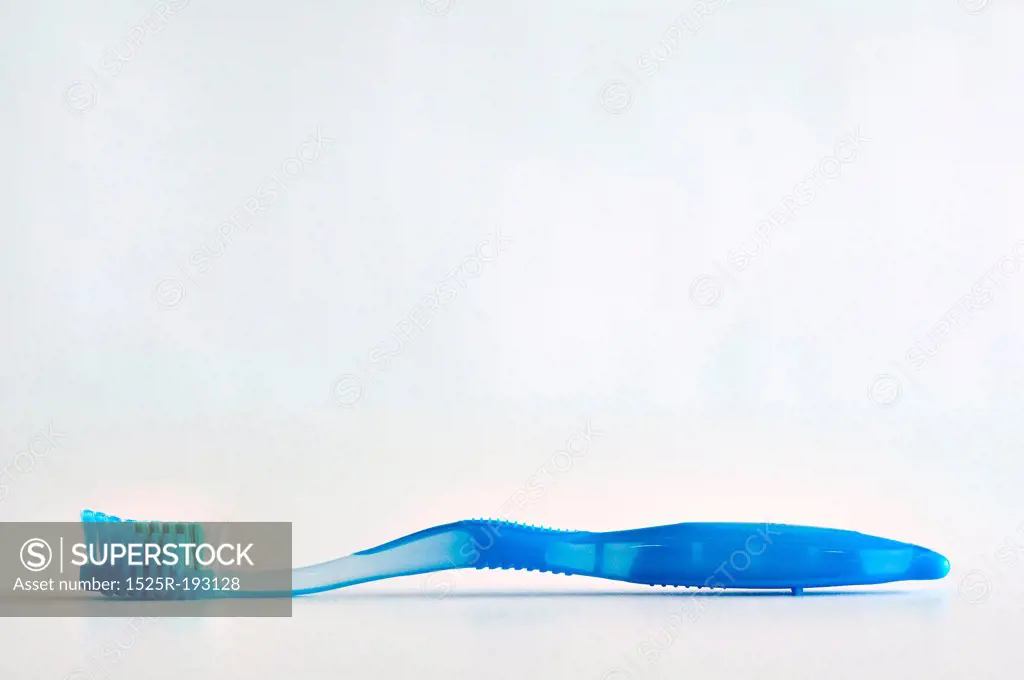 Single blue toothbrush lying face up on a white background.