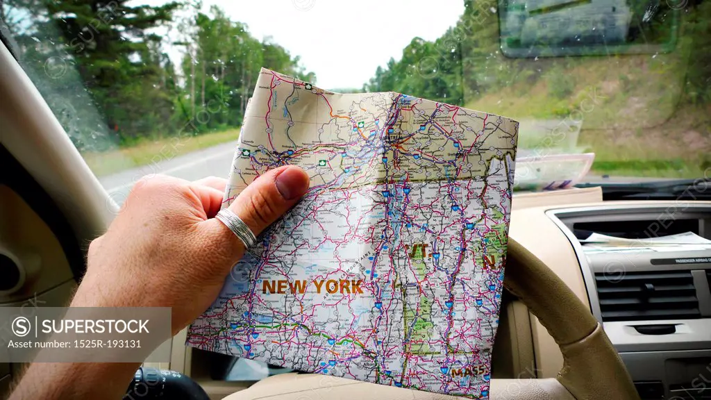 Traveling man looking at map of New York in car, while on road trip.