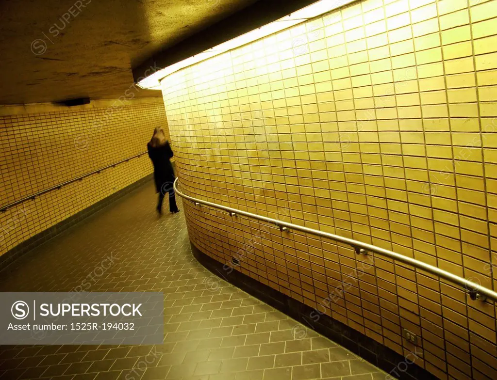 Women walking down underground subway corridor.