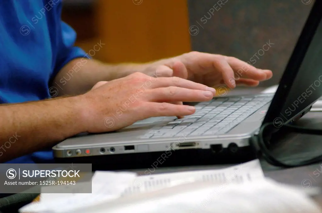 Man's hands typing on laptop.