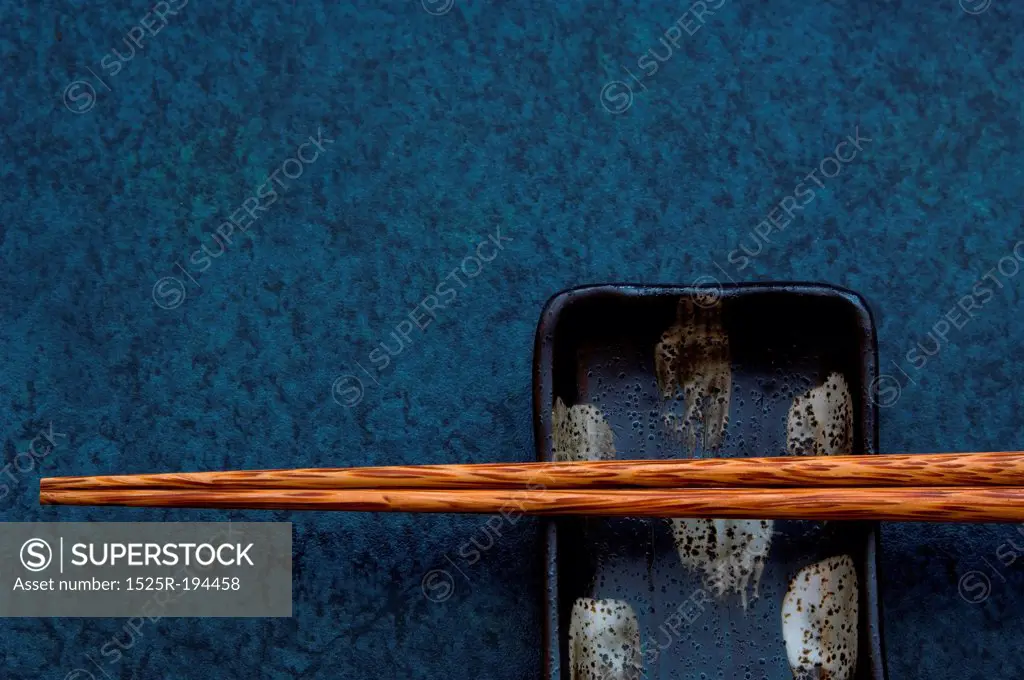 Chopsticks resting on small asian dish.