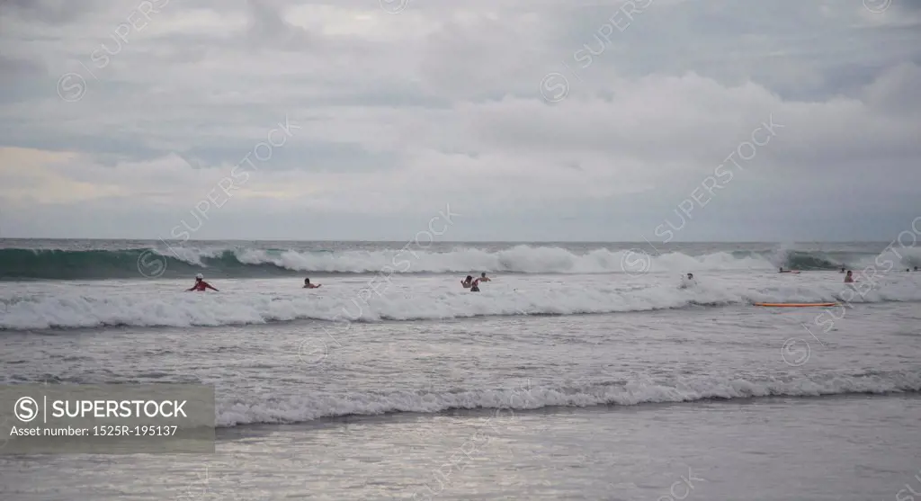 People swimming by shoreline in Bali