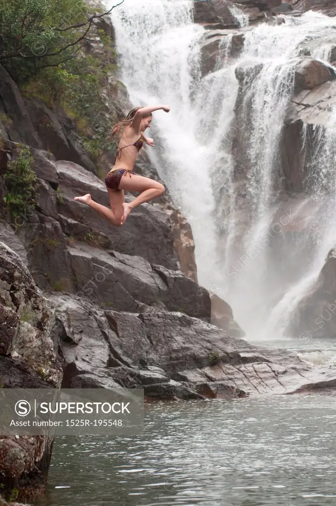Girl jumping from cliff at Mountain Pine Ridge Reserve, Waterfall