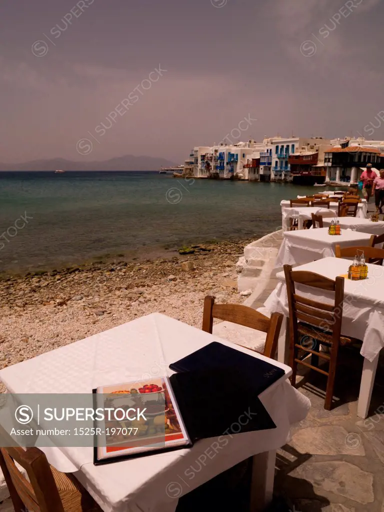 Empty table and chairs by seashore in Mykonos Greece