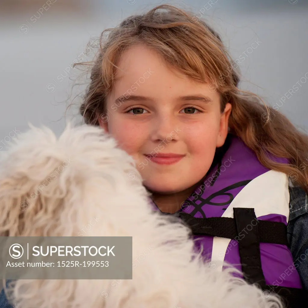 Young girl wearing a life jacket with her dog in Lake of the Woods, Ontario