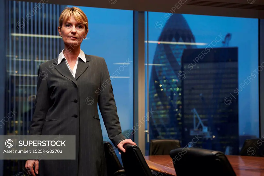 Serious Business woman leaning on chair in boardroom looking at camera