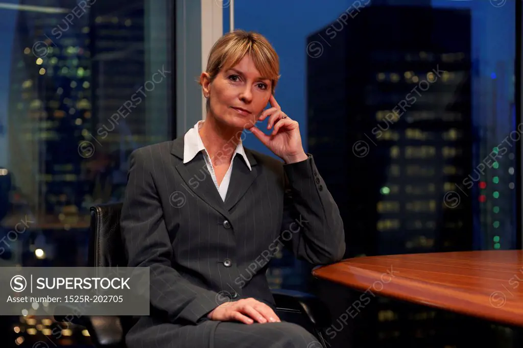 Business woman sitting at table in boardroom looking at camera