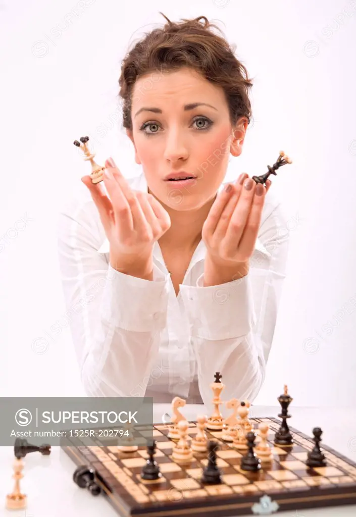 young woman holding chess pieces, looking at camera