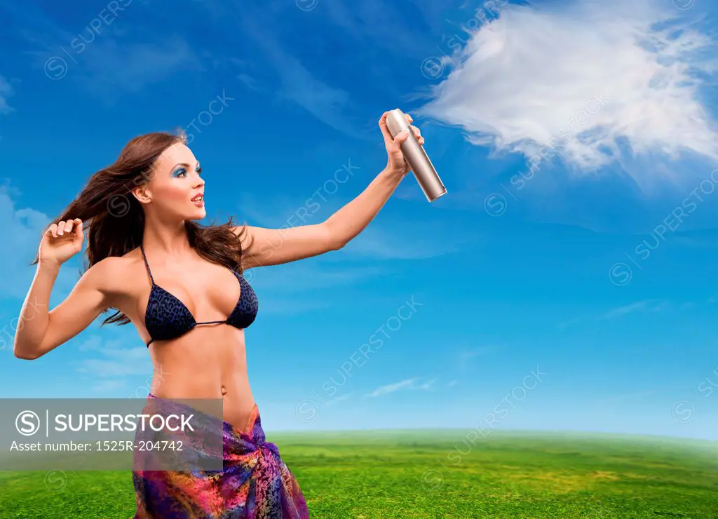 Young beautiful woman sprays clouds on a sunny day