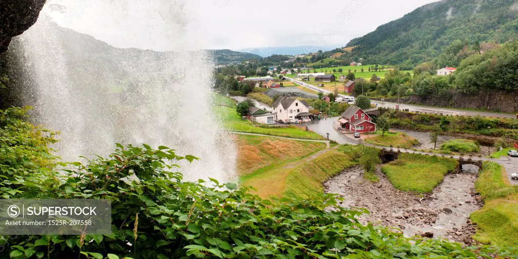 Waterfall with a village in the background, Steinsdalsfossen, Norheimsund, Hardanger, Hardangervidda, Hardanger, Norway