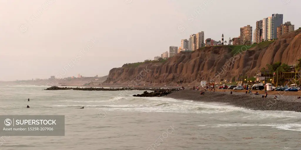 Tourists on the beach with a city in the background, Miraflores District, Lima Province, Peru