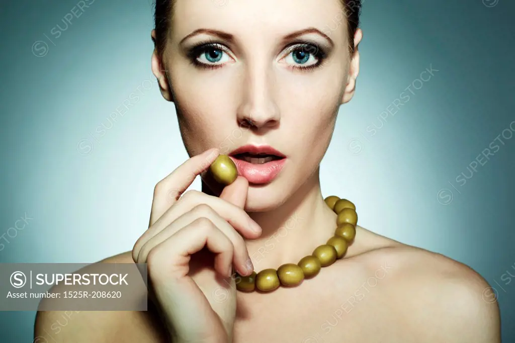 Portrait of the young beautiful woman with olives. An olive beads