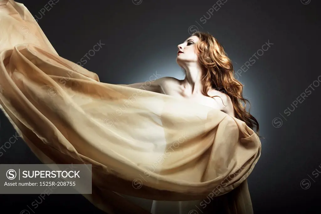 Portrait of the young woman against a flying fabric