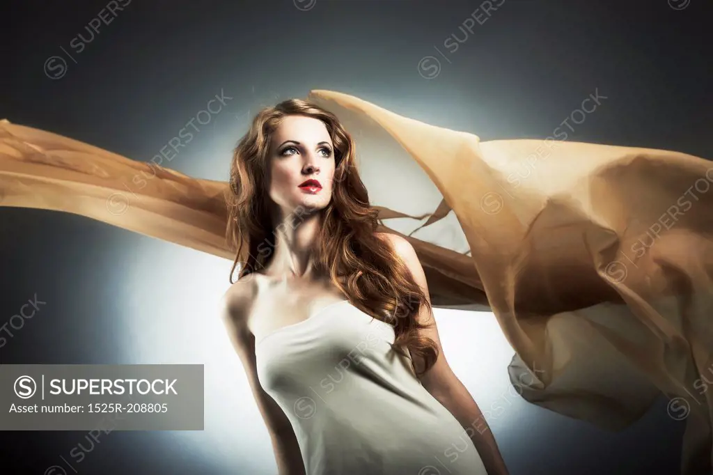 Portrait of the young woman against a flying fabric