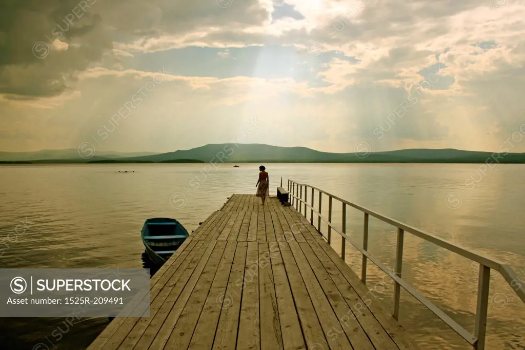 the girl  silhouette over the lake background