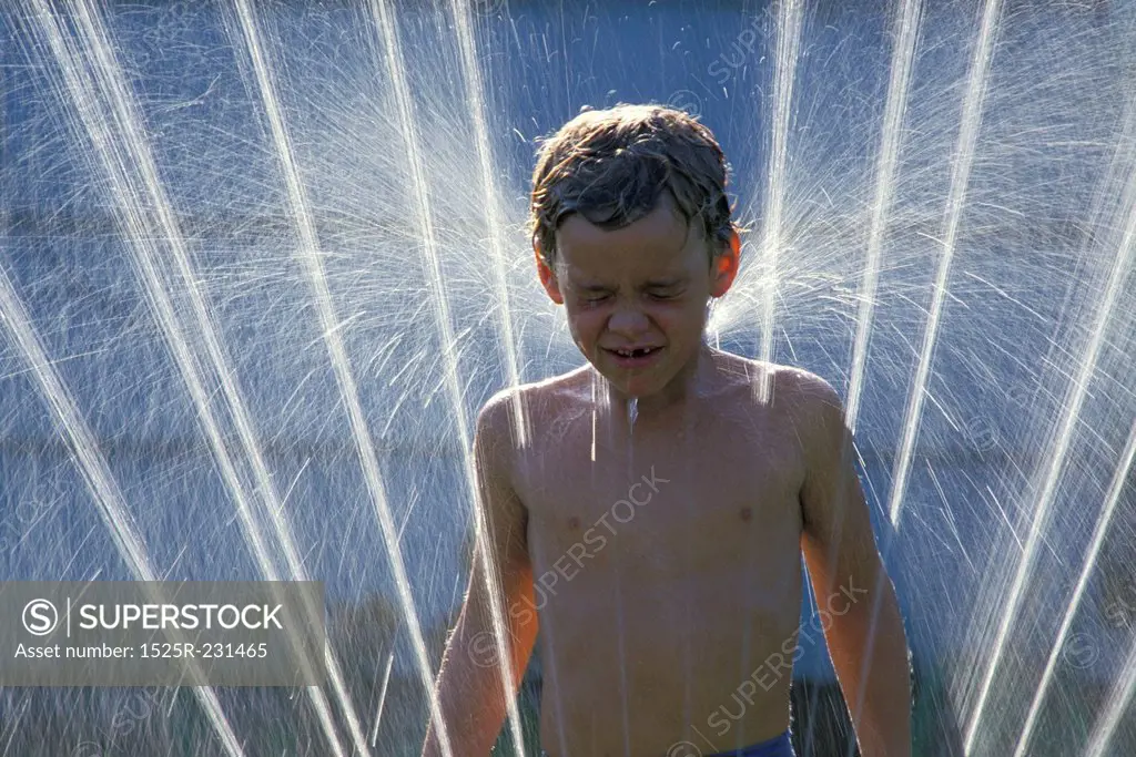 Little Boy Playing in Sprinkler