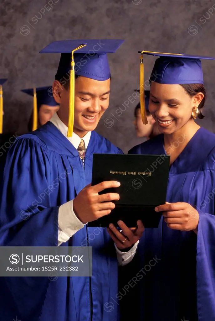 Graduates Smiling And Looking At Diploma