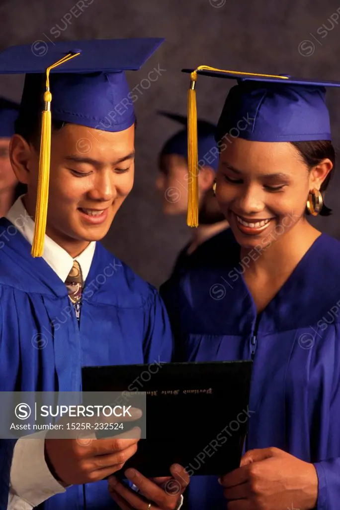 Graduates Looking At Diploma And Smiling