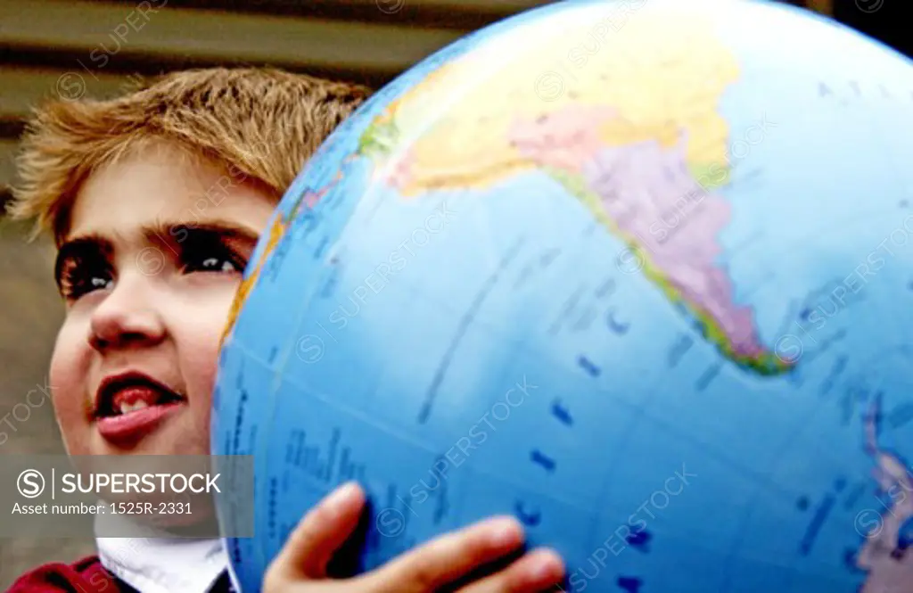 Close-up of a young boy holding a large globe