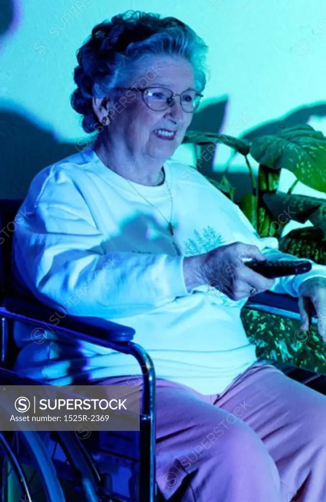A senior woman holding a remote control, watching TV