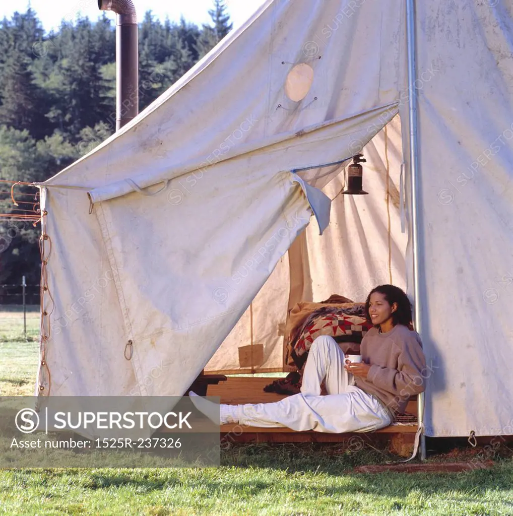 African American Woman Sitting Outside Her Tent On A Mountain Morning