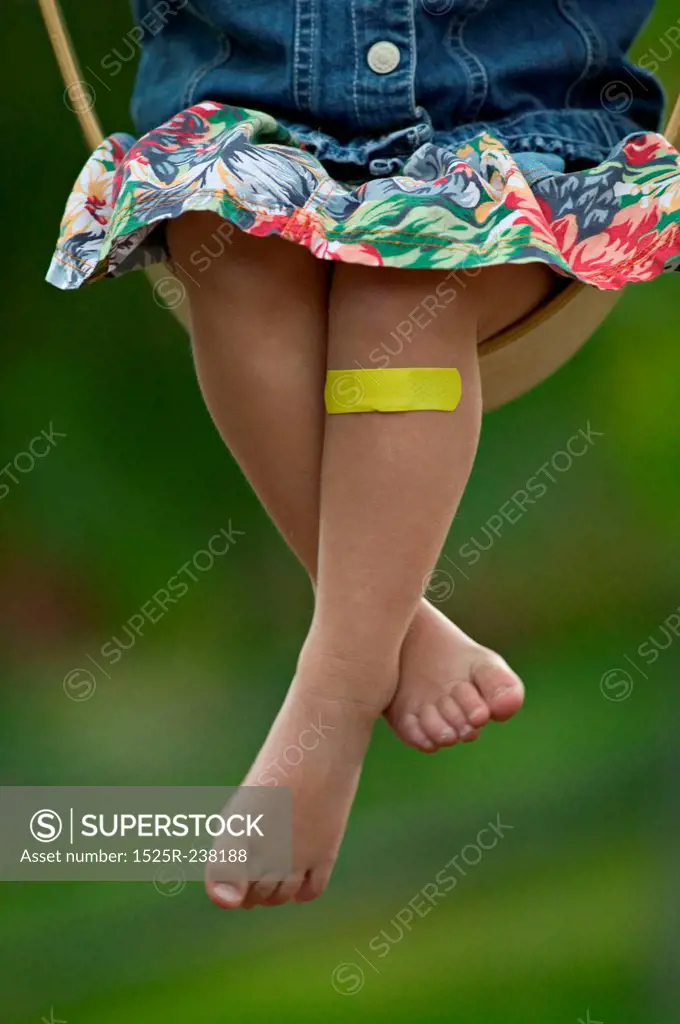 Girl Swinging With A Bandaid On Her Knee