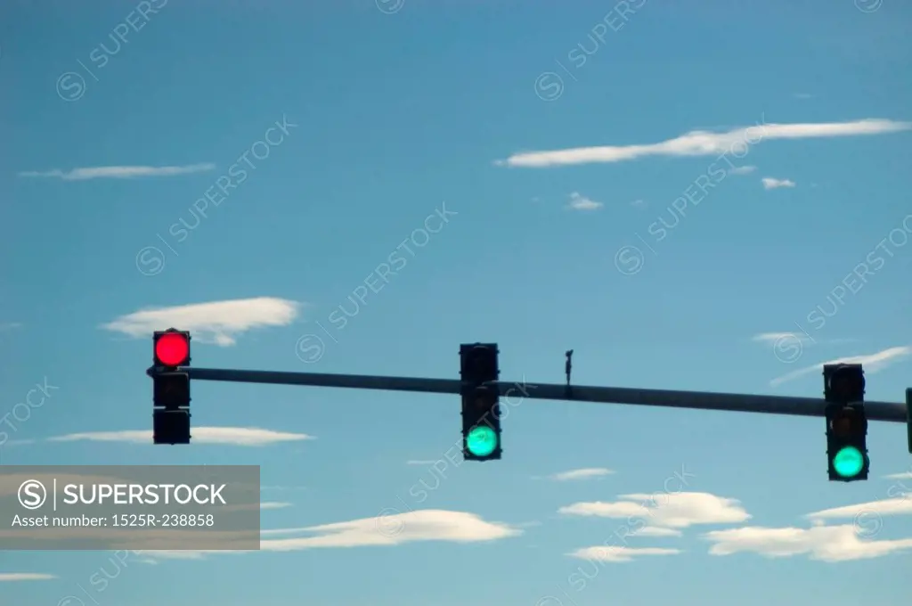 Red And Green Traffic Lights Hanging In A Blue Sky