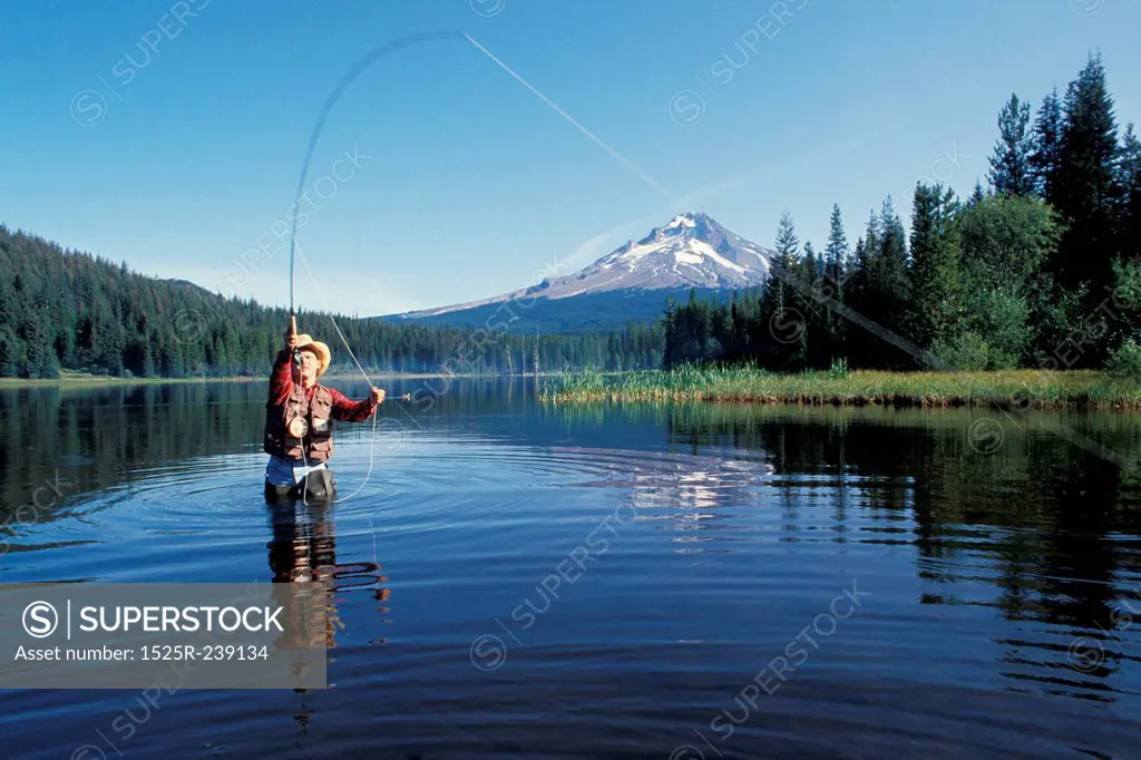 Caucasian Fly Fisherman Casting In A Mountain Lake