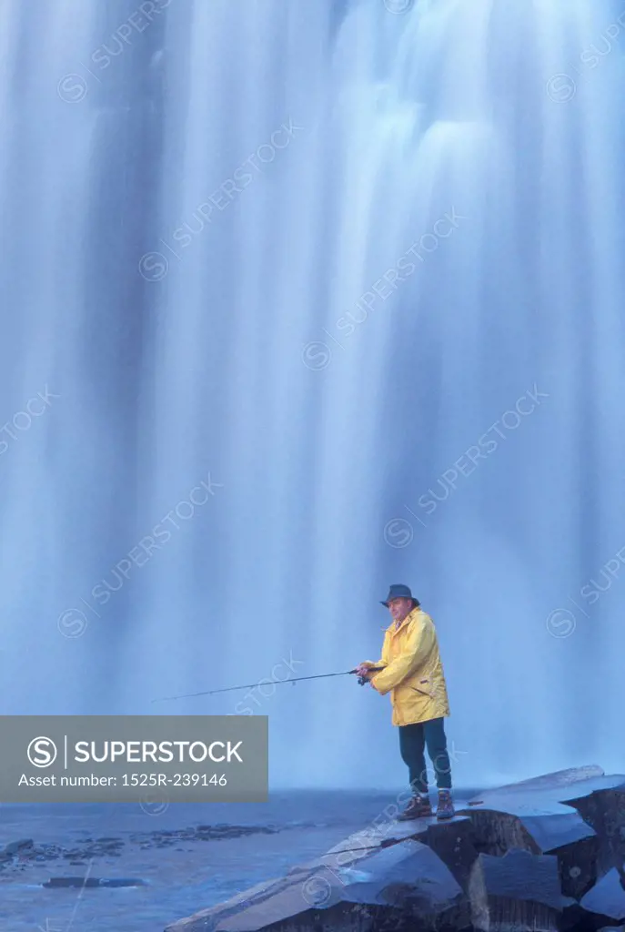 Man Fishing Under A Waterfall