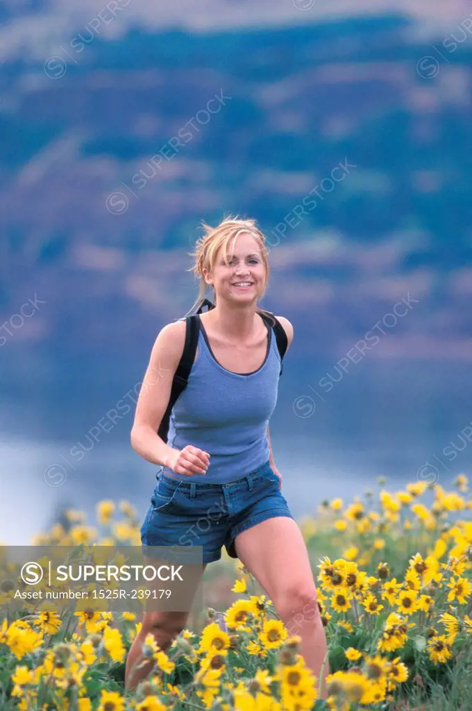 Woman Hiking Through Field of Yellow Flowers
