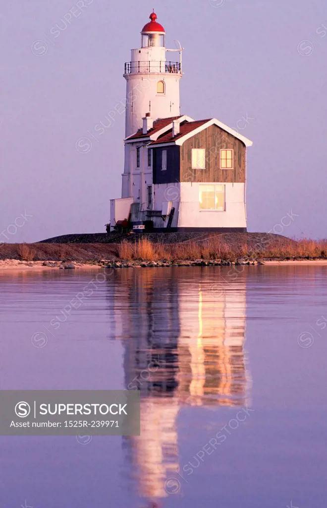 Reflection of old-fashioned lighthouse in calm ocean waters