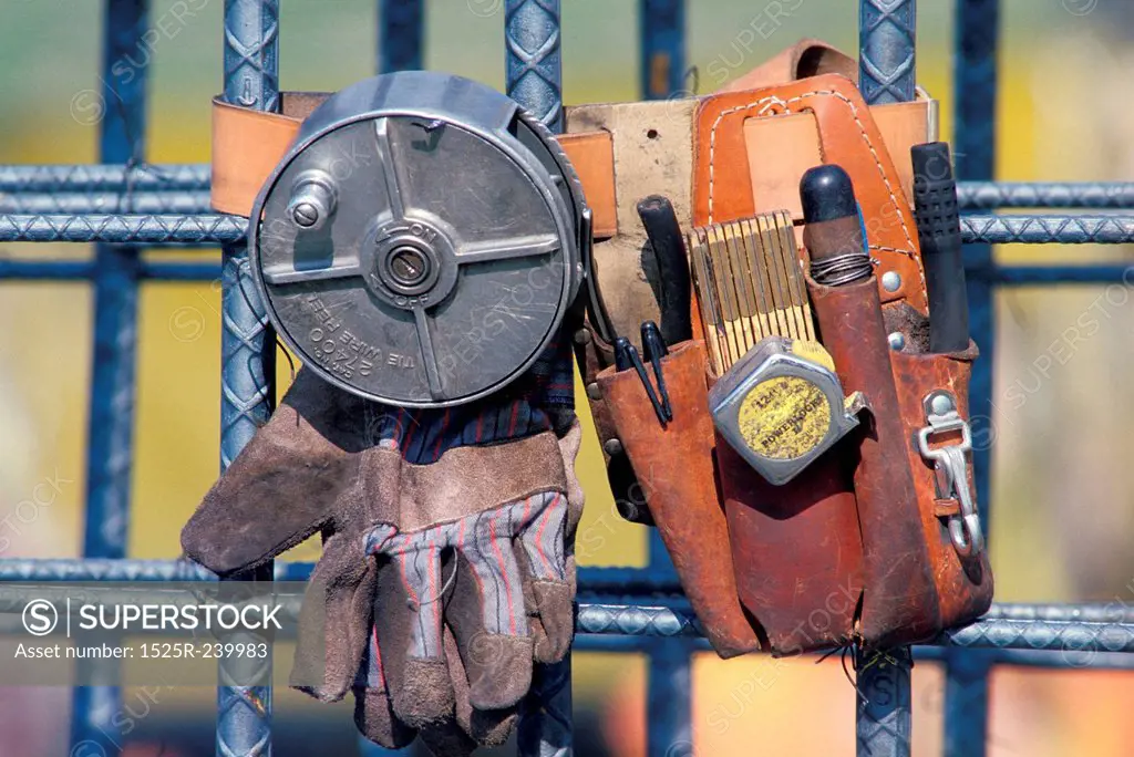 Close up of construction workers equipment: gloves, tool belt, measuring tape, pliers