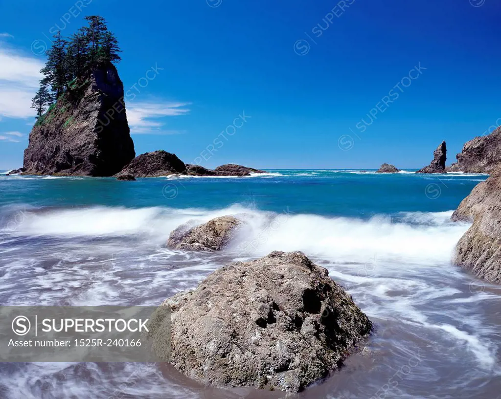 Blurred motion shot of ocean water swirling around rock with rock formation in background