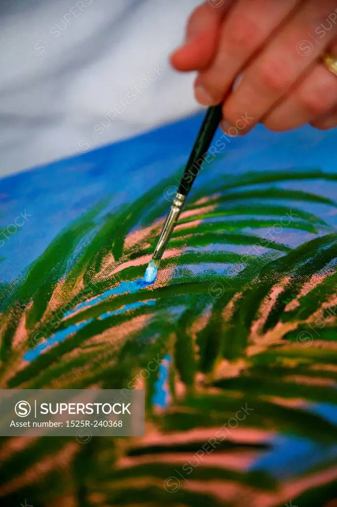 Close up of artist painting shrub with paintbrush and oil paints