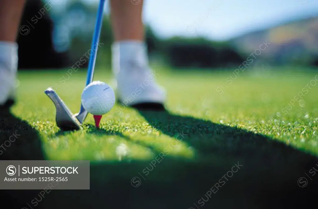 Close-up of a golf club near a golf ball on a tee
