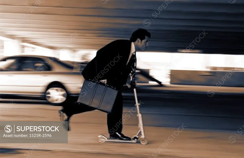 Businessman carrying a briefcase, riding a scooter
