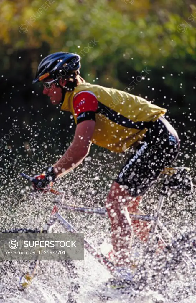 A young man cycling in a stream