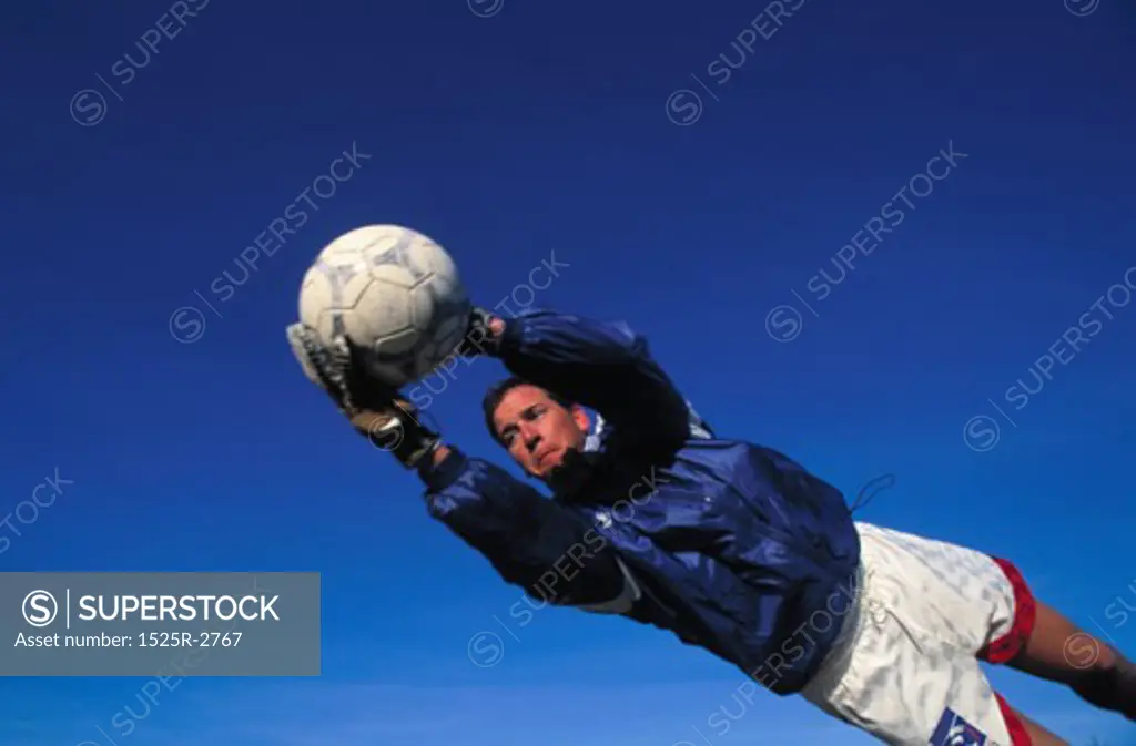 Low angle view of a male goalie jumping to stop a ball