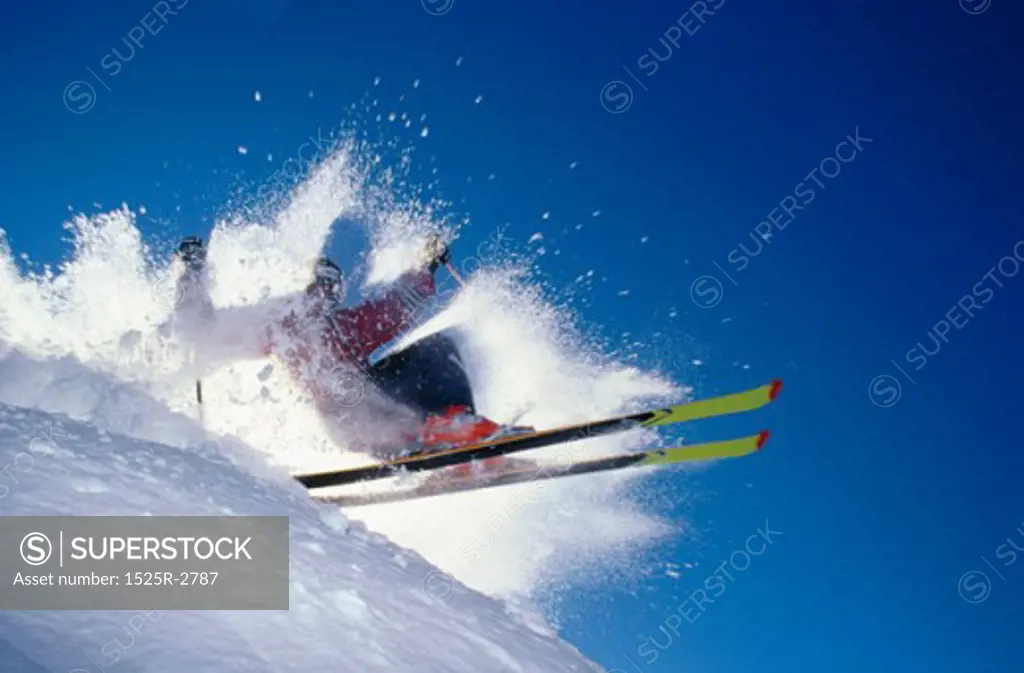 Low angle view of a skier throwing up snow while skiing on a mountain