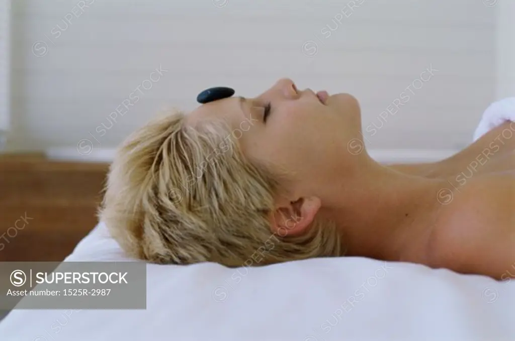 Side profile of a young woman getting stone therapy