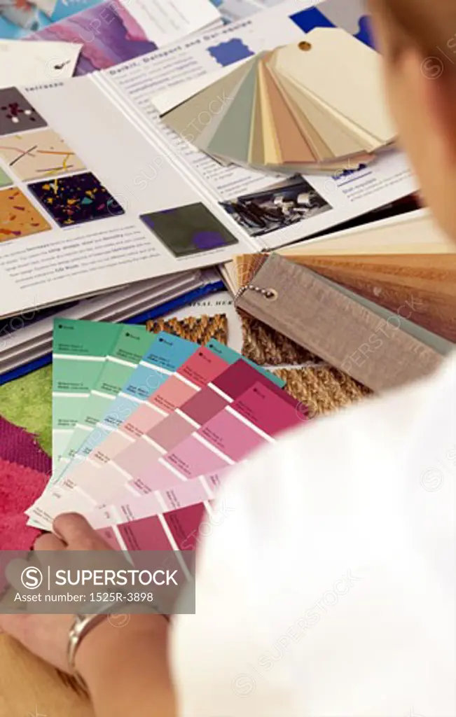 Close-up of a woman looking at shade cards of paints on a table