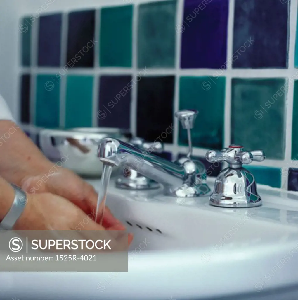 Close-up of a person washing their hands in a wash basin