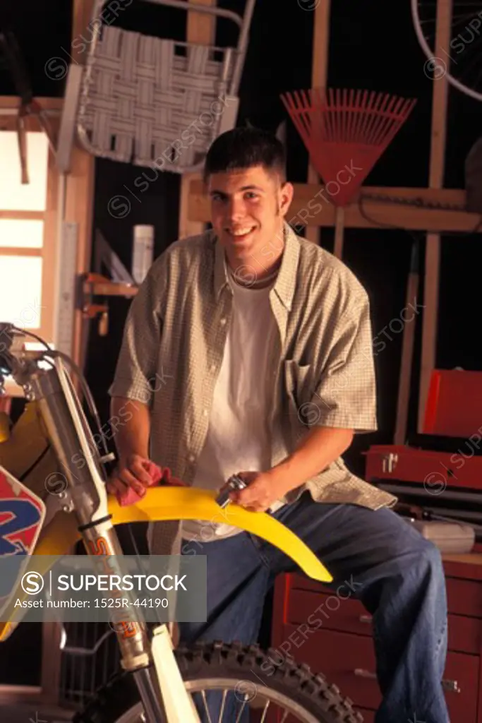 Teenage Boy Standing Next To Dirt Bike In Garage