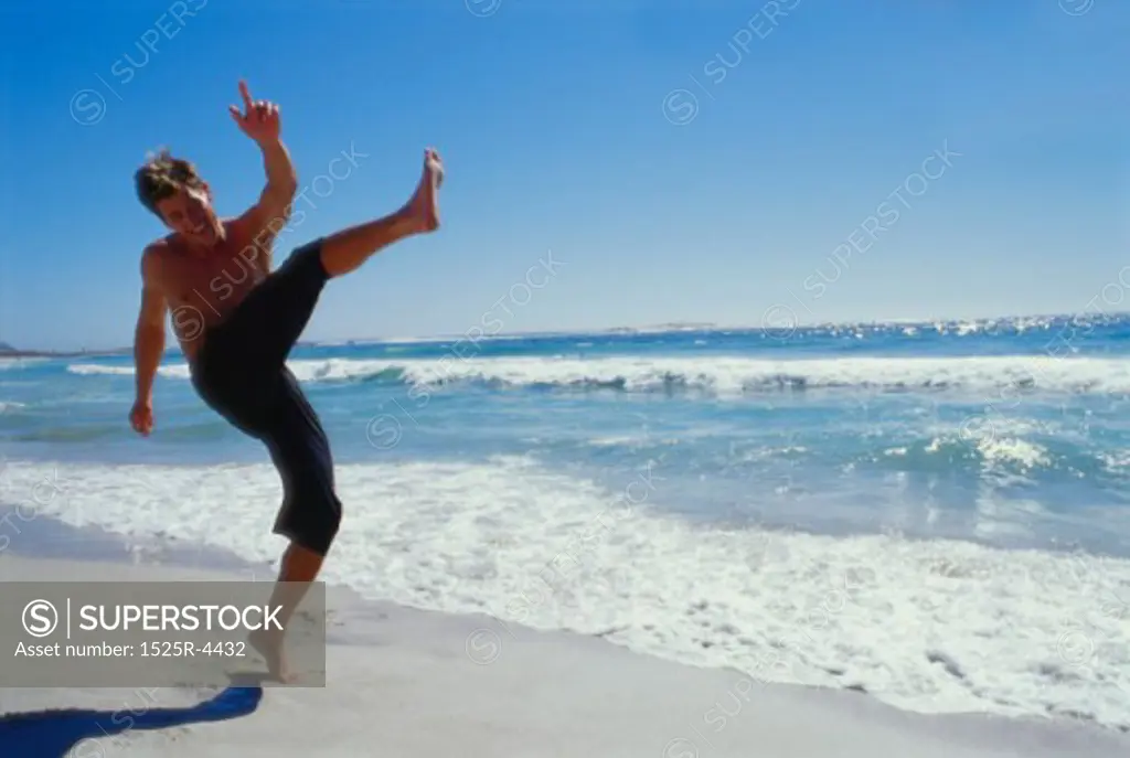 Young man kicking on the beach