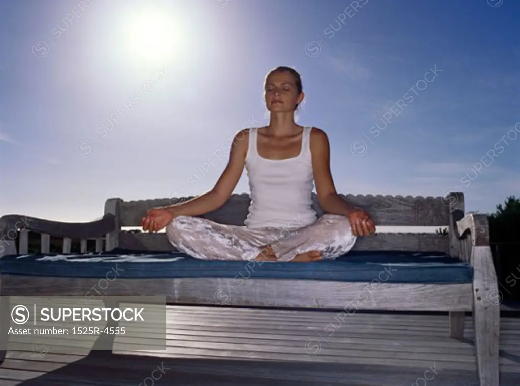 Low angle view of a young woman practicing yoga on a bench